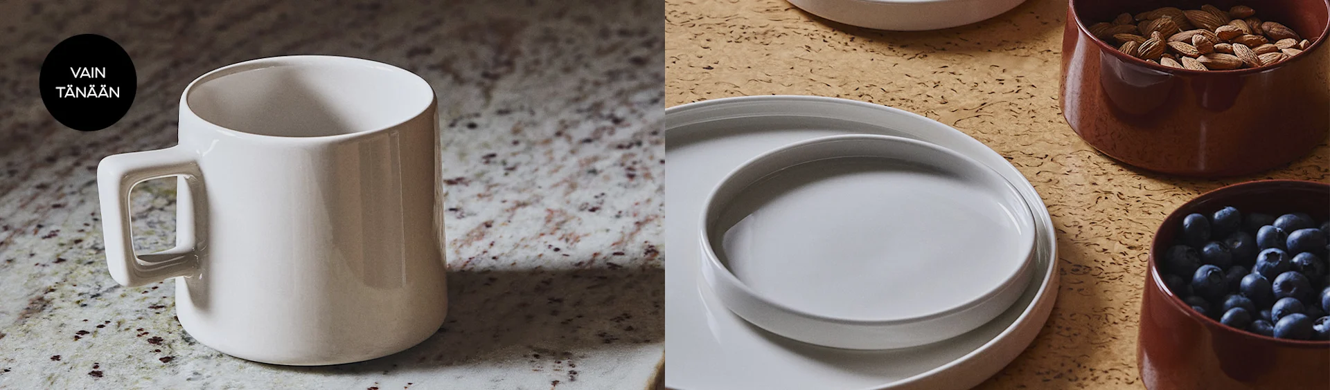 Valkoinen muki täplikkäällä pinnalla. Oikealla vaaleanharmaita lautasia, ruskea kulho manteleilla ja toinen mustikoilla teksturoidulla pinnalla.