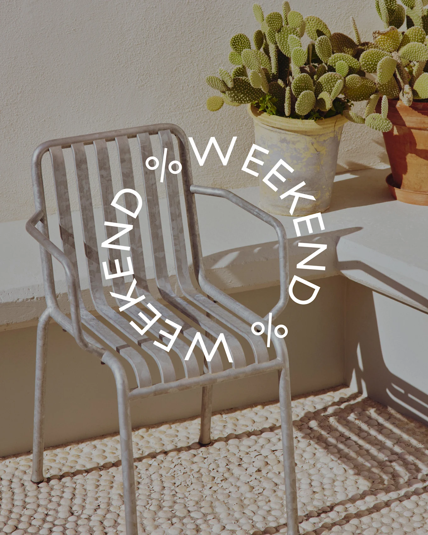 Harmaa metalliritilätuoli ruukkukaktuksen vieressä, jossa pyöreä teksti 'WEEKEND % WEEKEND %'.