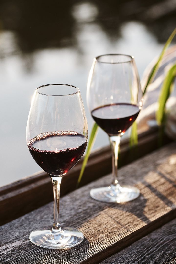 Miten valita oikeanlainen viinilasi - tässä näet merkin Scandi living Karlevi-lasit punaviinin kanssa. Seisomassa terassilla. 